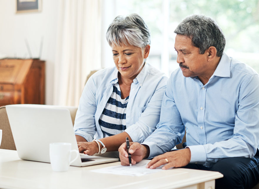Husband and wife looking at their Ariston Credit Union account on the computer together.